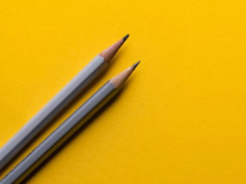 Zwei Bleistifte auf gelbem Grund