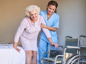 Altenpflegerin stützt Seniorin
