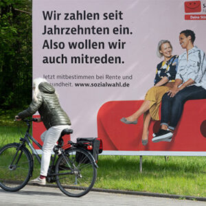 Straßenszene mit Plakat zur Sozialwahl 2023