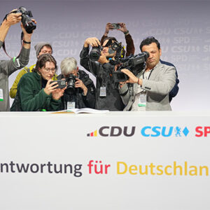 Das Foto zeigt Journalisten die eine unterzeichnete Ausfertigung des Koalitionsvertrages zwischen CDU, CSU und SPD filmen und fotografieren.