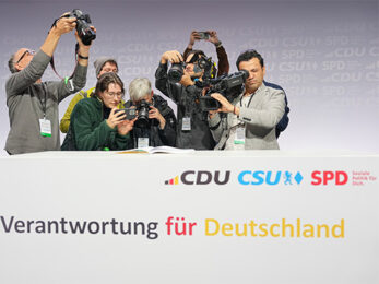 Das Foto zeigt Journalisten die eine unterzeichnete Ausfertigung des Koalitionsvertrages zwischen CDU, CSU und SPD filmen und fotografieren.