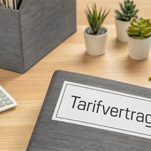Das Foto stellt einen Aktenordner dar, der auf einem Schreibtisch liegt, mit Aufschrift: Tarifverträge