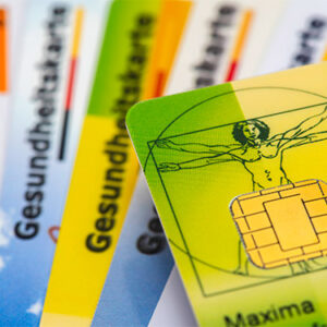Das Detail einer Krankenkassenkarte mit Chip liegt über einigen Gesundheitskarten verschiedener Krankenkassen.